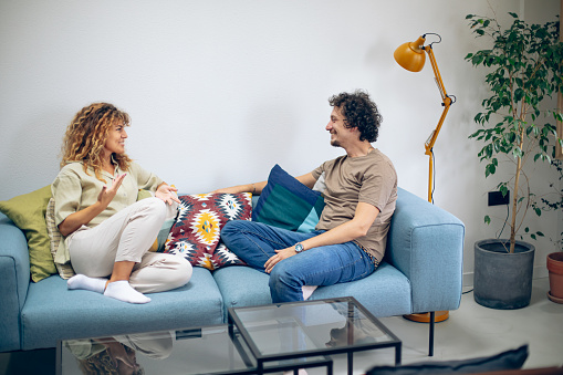 Young couple sitting on a sofa in living room, talking