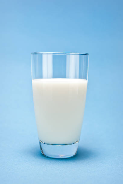 Glass of fresh milk on blue background