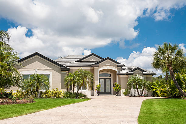 New Luxury Home with Palm Trees. "New luxury home in the tropics with driveway, palm trees, lush tropical foliage, front lawn." florida stock pictures, royalty-free photos & images
