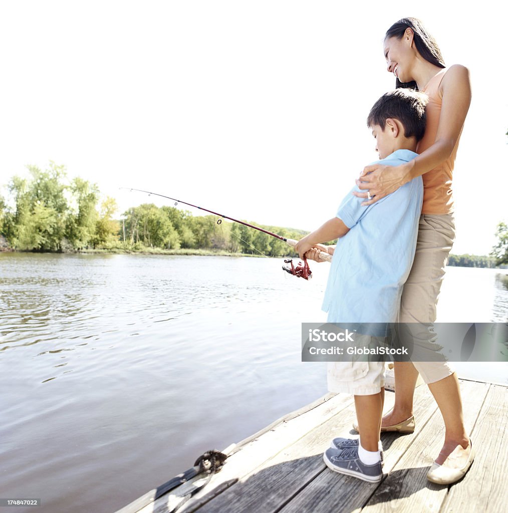 You just had a nibble! A happy mother hugging her son as he learns to fish Adult Stock Photo