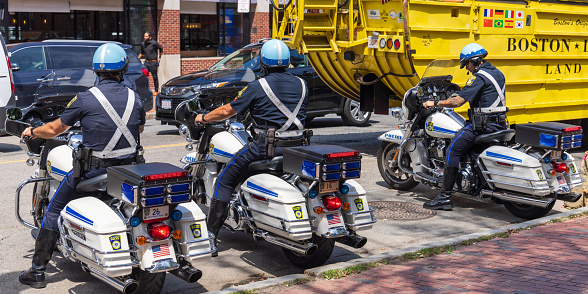 Boston, Massachusetts, United States - August 9, 2023: Three motorcycle policemen about to drive off into traffic