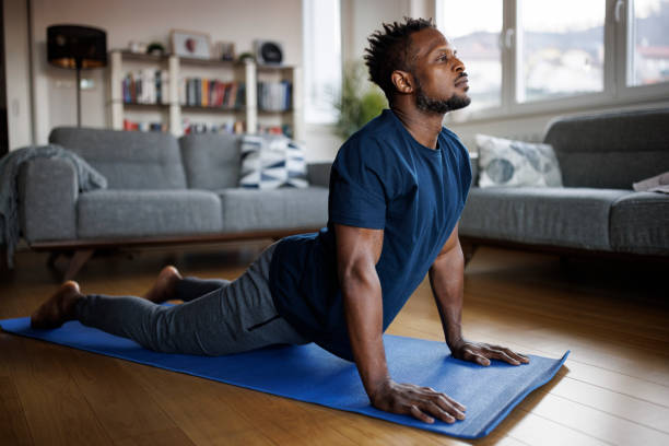 Uomo che pratica yoga, allungamento dei muscoli, sdraiato nella posizione del cobra - foto stock