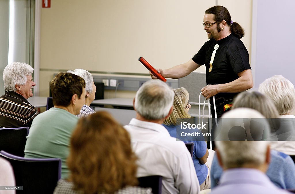 Magician Performing Trick Group of seniors sitting in the lecture room and watching magician performing a magic trick. Magician Stock Photo