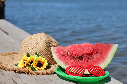 slice of red watermelon, red glasses, a green plate and a straw hat