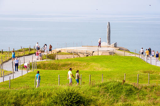 Cricqueville-en-Bessin, France - Sept. 6, 2023: Tourists wander on the Pointe du Hoc path between bomb craters to the Ranger Monument erected in honor of the sacrifice of American troops on D Day.