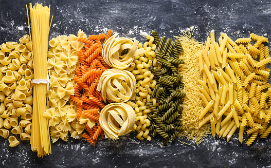 Variety of dry Italian pasta on black table. Top view. Website header, banner