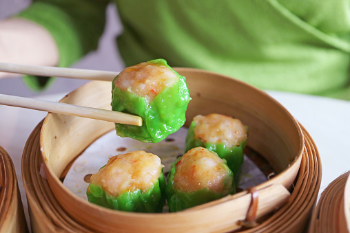 Closeup of Shumai, Shrimp and Pork Filled Chinese Steamed Dumpling Being Picked with Chopsticks