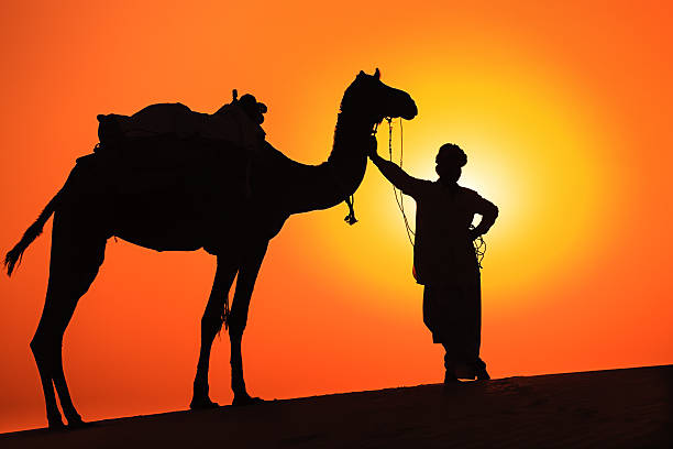 istock Indian man with camels during crossing sandunes 174849211