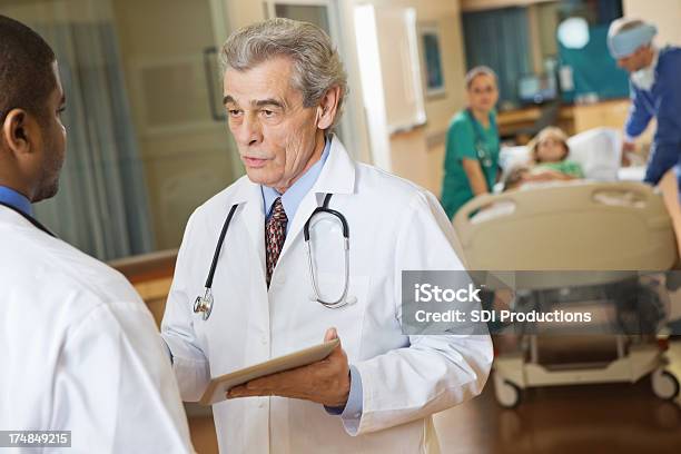 Medico Senior Di Formare I Colleghi In Corridoio Ospedale Occupato - Fotografie stock e altre immagini di Adulto