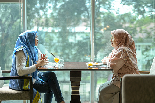 Mature women are discussing near the window