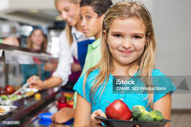Young Girl In Cafeteria Línea Con Frutas Y Verduras Foto de stock y más banco de imágenes de Bandeja