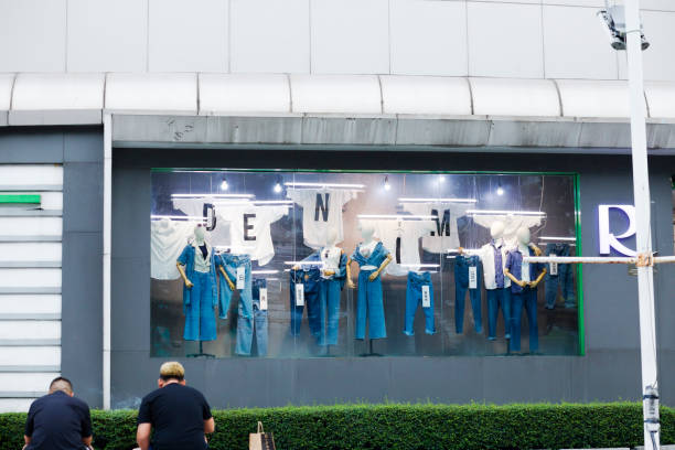 Window of mall decorated with jeans and capital  letters DENIM. Window is of Robinson store in shopping mall Central Plaza Rama 9 at Ratchadaphisek Rd. in Bangkok.  In bottom left area some men are sitting and are having a break