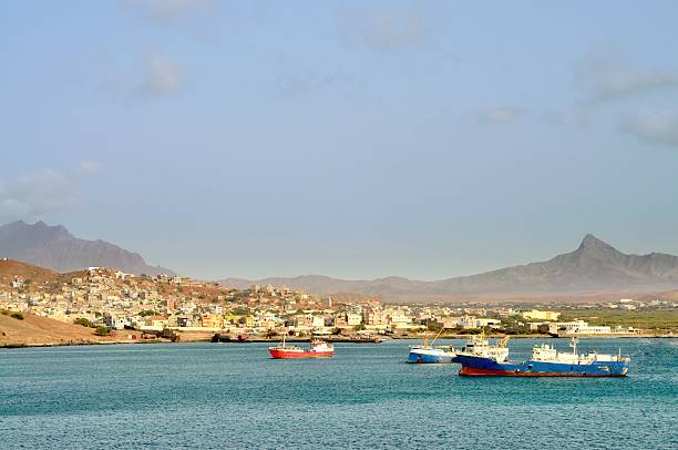 Mindelo Marina Scene The harbor at Mindelo with cargo ships riding at anchor to avoid paying docking fees. The city goes up the slope to the foothills of the volcanic mountain range that formed the islands. porto grande stock pictures, royalty-free photos & images