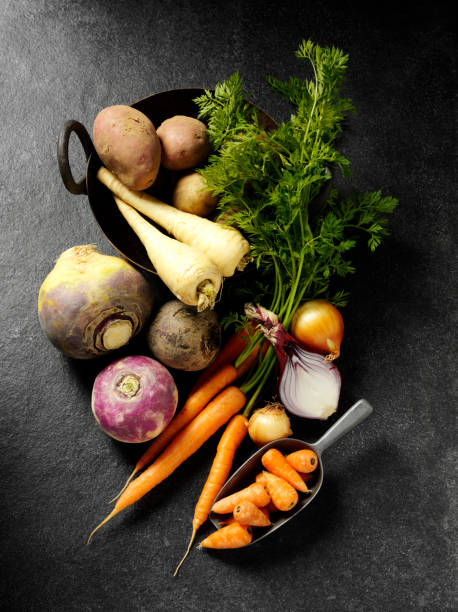 Root Vegetables on a Slate Background "A group of root vegetables such as parsnips, swede, beetroot,onion,potatoes and carrots, in a metal bowl on a slate background.Click on the link below to see more of my fruit and vegetable images" turnip stock pictures, royalty-free photos & images