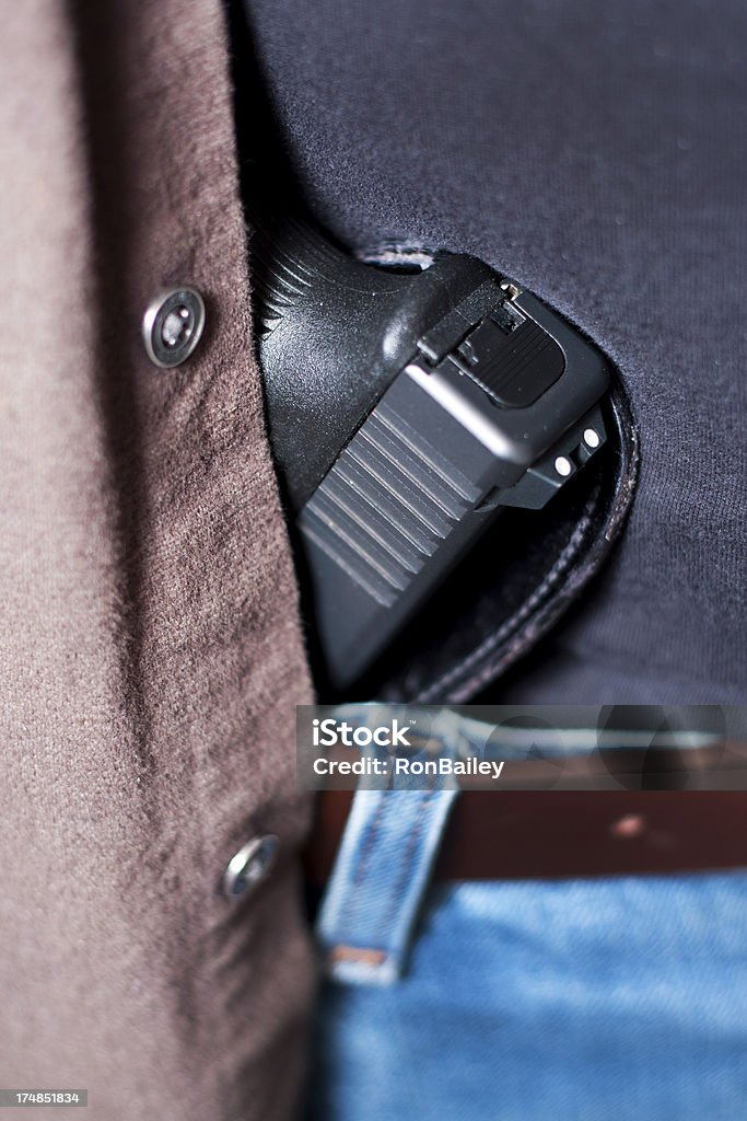 Concealed Firearm Under Shirt "A modern, polymer (Glock), .45 caliber semiautomatic pistol in an inside-the-waistband (IWB) holster behind a loose-fitting shirt.All images in this series..." Concealed Carry Stock Photo