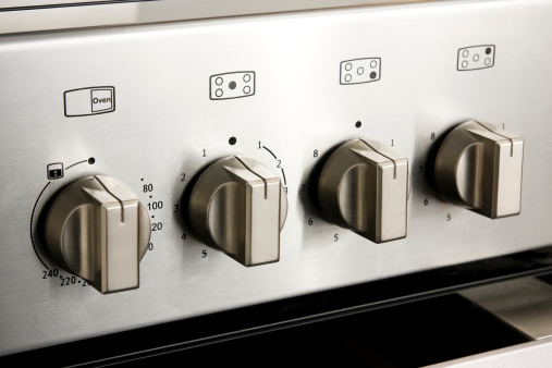 Metallic oven and hotplate dials on a kitchen cooker close-up.