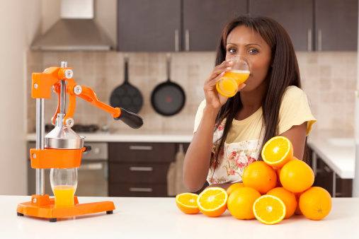 Woman drinking freshly squeezed orange juice. Woman squeezing orange slices and making juice.