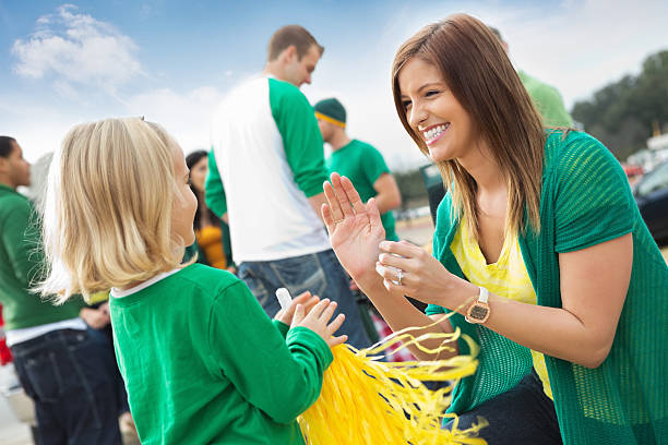 Mom and daughter cheering with friends tailgating at college stadium Mom and daughter cheering with friends tailgating at college stadium. people family tailgate party outdoors stock pictures, royalty-free photos & images