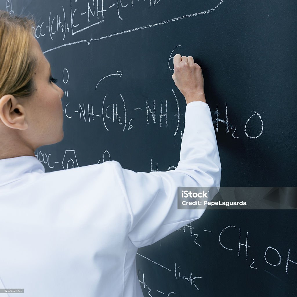 Teaching chemistry Young woman in a chemistry class, writing formulas on blackboard. 30-34 Years Stock Photo