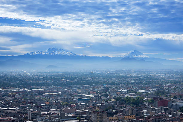 mexico city volcanoes "Panoramic view of the Valley of Mexico from the city downtown at sunrise with the volcanoes popocatepetl, iztaccihuatl covered in snow and surrounded by clouds and fog" popocatepetl volcano photos stock pictures, royalty-free photos & images