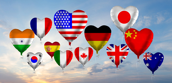 Flags of different countries on the background of the blue sky with clouds in the sunlight