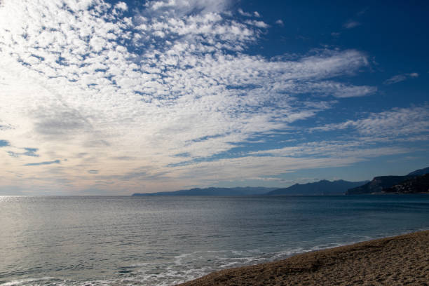 Varigotti beach in Liguria during an early January day, with layered clouds in the sky and sun reflected on the sea water