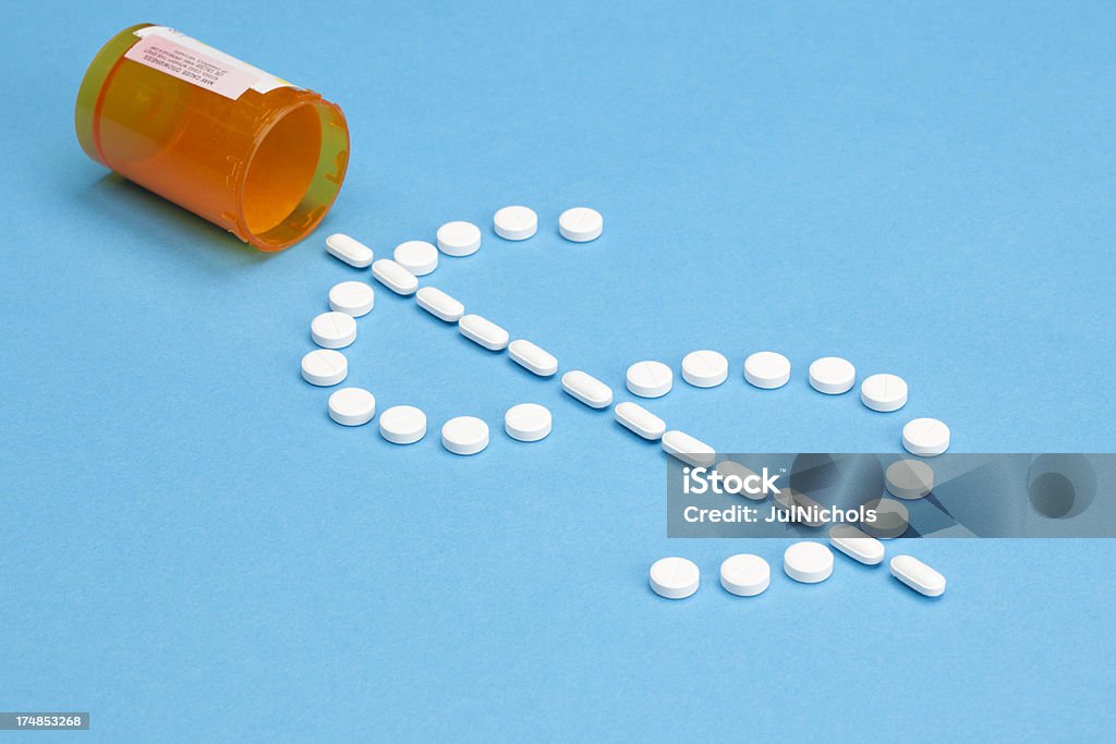 High Costs of Prescription Medicine or Healthcare High costs of Prescription Medicine concept image. White pills in the shape of a dollar sign spilling from a prescription pill bottle onto a blue background. Shallow depth of field.Please also see: Price Tag Stock Photo