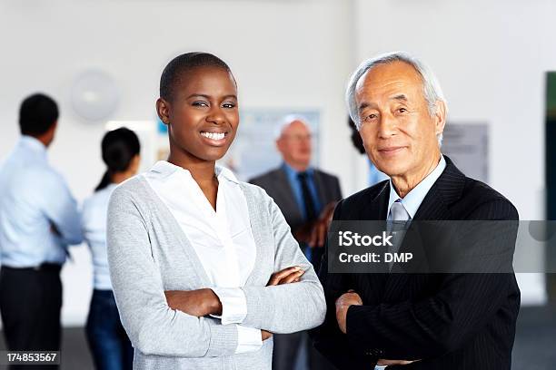 Dos Profesionales De Los Negocios Con Colegas En Fondo Foto de stock y más banco de imágenes de Adulto