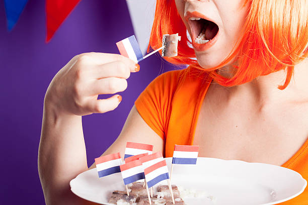 оранжевый поклонник ест сельдь - fan dutch flag women colors стоковые фото и изображения