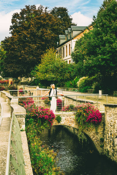 Female tourist relaxing by a small stone bridge over the Iton River in the town of Evreux, west of Paris, France.