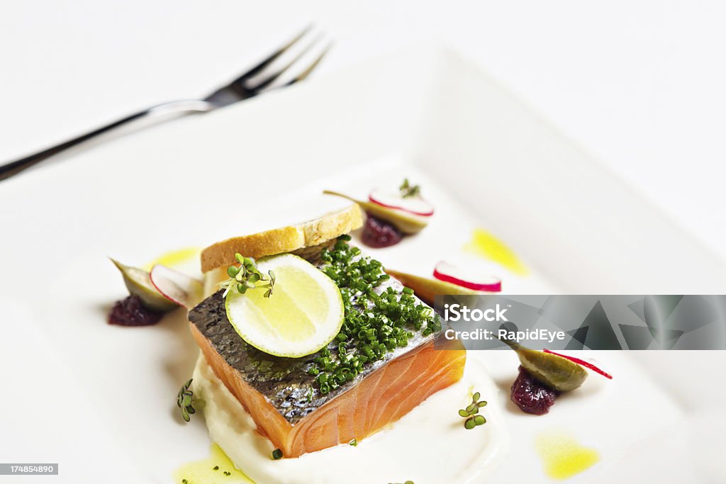 Looking down at gourmet dish of salmon with caper berries "Delicious and beautifully presented restaurant dish of smoked salmon, served with caper berries, radishes, red onion gel, lime yogurt and rosemary toast. A gourmet meal." Bruschetta Stock Photo