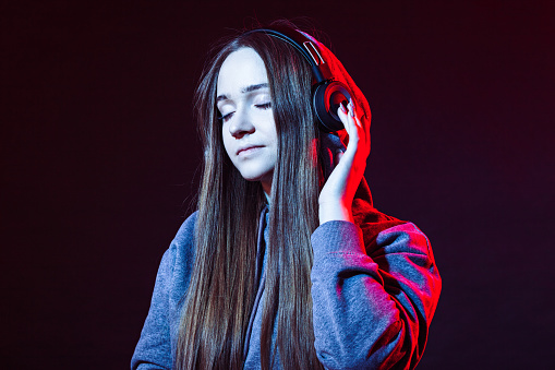 Studio portrait of a 20 year old woman listening to music on wireless headphones