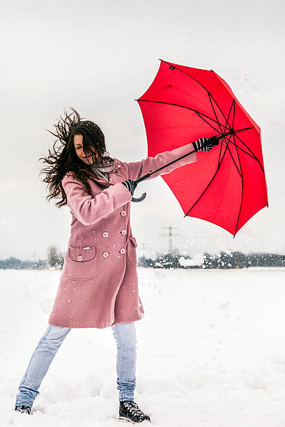 istock Young female holding umbrella on windy winter day 174855980