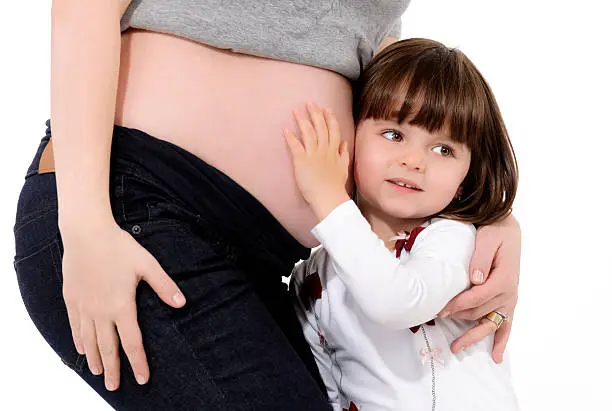little girl listening her mother's tummy, white background.