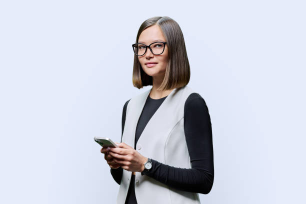 istock Young confident woman with smartphone in hands on white studio background 1748567775