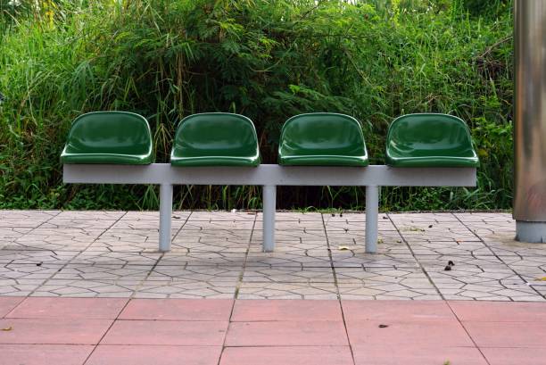 A bus stop with a green chair on foot sidewalk.