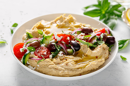 Greek style vegan mediterranean hummus with fresh vegetables, olives, olive oil and feta cheese