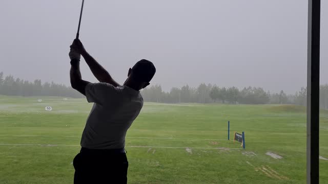 Pro golf is practicing at golf driving range.