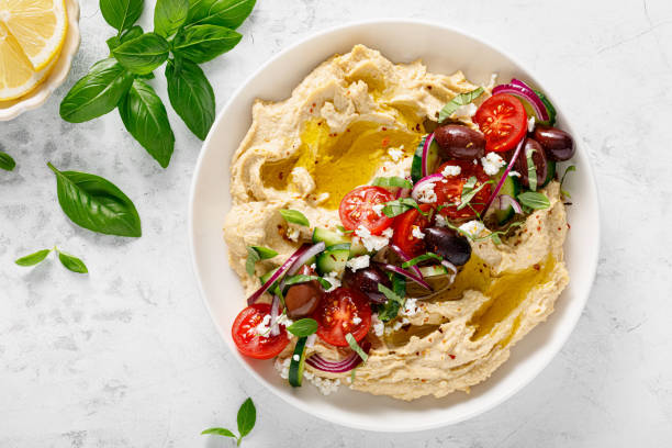Greek style vegan mediterranean hummus with fresh vegetables, olives, olive oil and feta cheese. Top view Greek style vegan mediterranean hummus with fresh vegetables, olives, olive oil and feta cheese. Top view hummus stock pictures, royalty-free photos & images