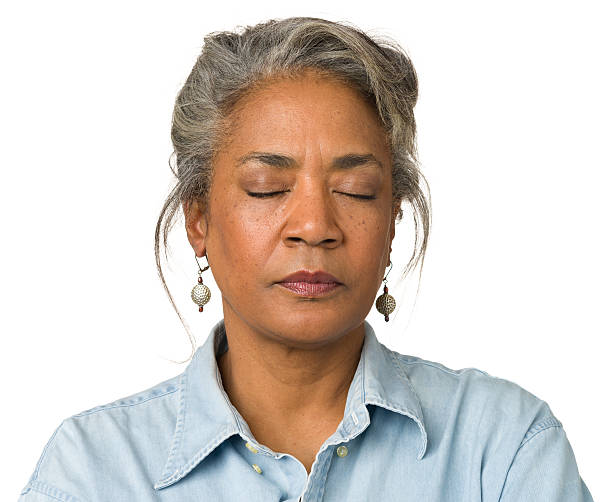 gray haired woman wearing droplet earrings with eyes closed - ogen dicht closeup vrouw 50 jaar stockfoto's en -beelden