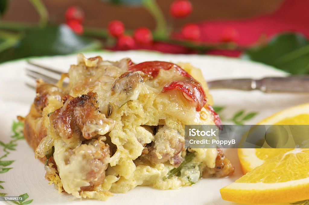 Serving of Sausage Breakfast Casserole Serving of sausage breakfast casserole or strata on china plate with orange slices and fork Breakfast Stock Photo