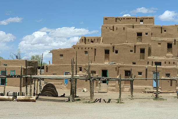 Taos Pueblo New Mexico "Sitting in the shade, a dog rests near a beehive oven in front of the Native American landmark of Taos Pueblo in New Mexico." stove oven adobe outdoors stock pictures, royalty-free photos & images