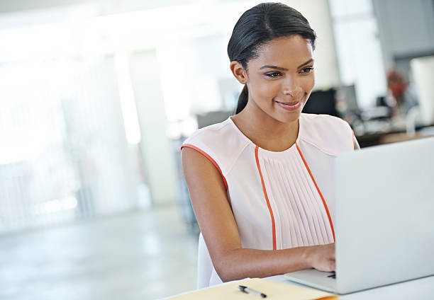 istock A woman in a large office space working at a computer 174860338
