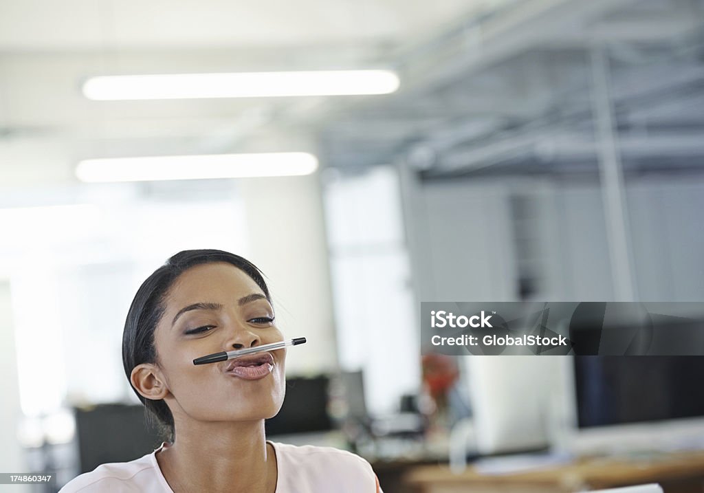 Office antics Shot of a bored office worker balancing a pen on her lips Pen Stock Photo