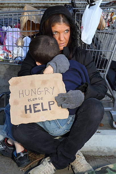 obdachlos frau hält sohn vertikal - street child stock-fotos und bilder