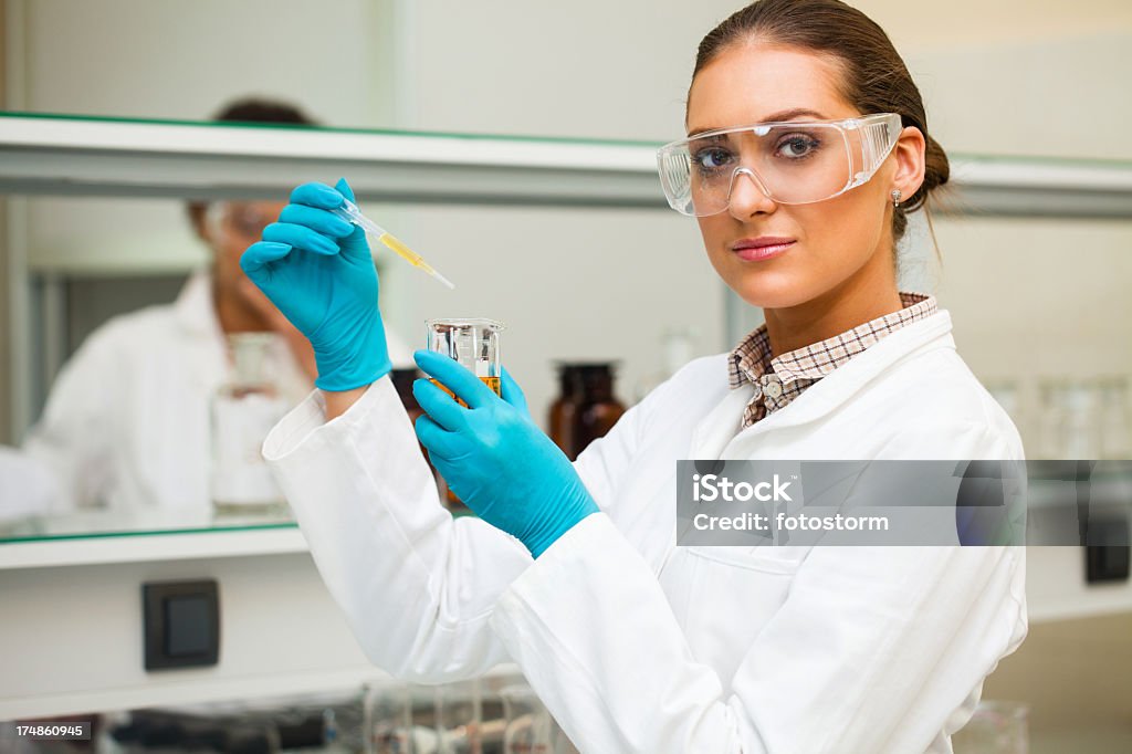 Pipetas mujer científico muestra amarillo - Foto de stock de Científico libre de derechos