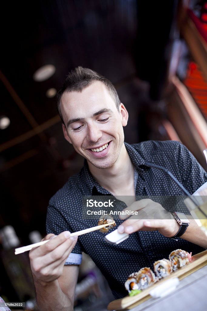 Hombre joven feliz comiendo Sushi - Foto de stock de 20 a 29 años libre de derechos