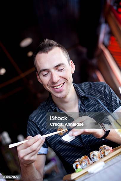 Hombre Joven Feliz Comiendo Sushi Foto de stock y más banco de imágenes de 20 a 29 años - 20 a 29 años, Adulto, Adulto joven