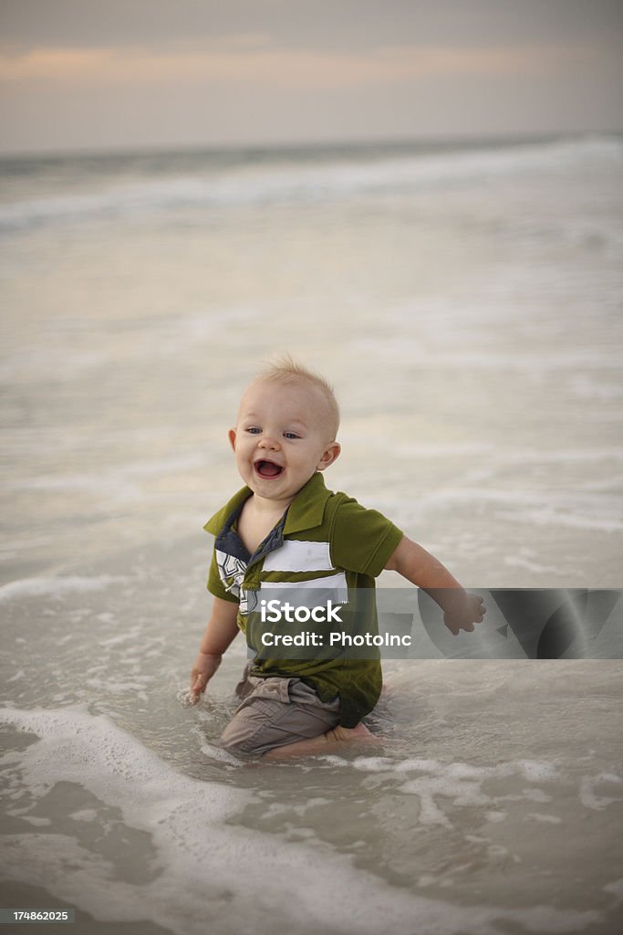 Bambino ragazzo giocando nel Surf - Foto stock royalty-free di Abbigliamento