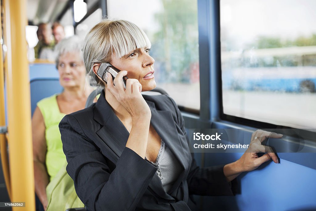 Empresária como meio de transporte por ônibus e falando no telefone celular. - Foto de stock de Assento de veículo royalty-free